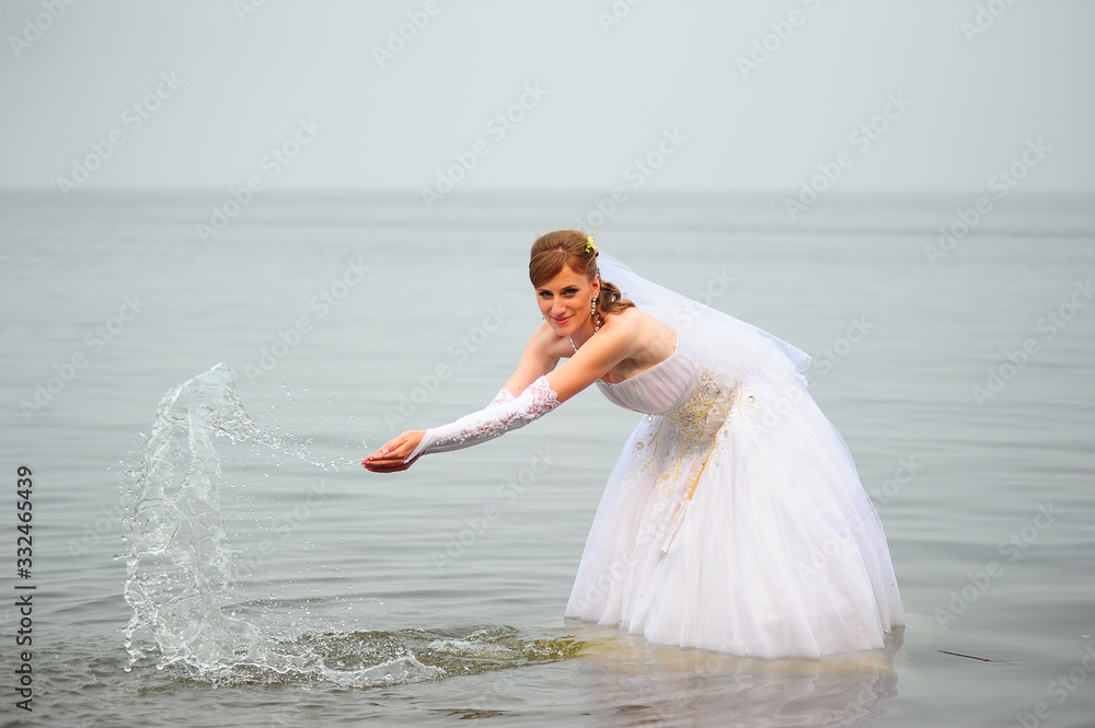 Naklejka premium Bride in a wedding dress on a wakeboard slides on the lake.