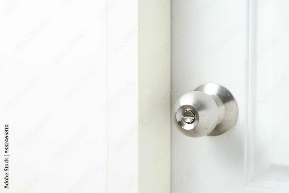 Silver doorknob on white wooden door of bathroom. Silver doorknob on white wooden door of bathroom.