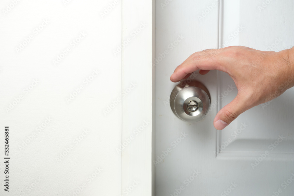 Hand going to hold the doorknobs of the closed white door. Health concept to aware for touching the everyday objects. Hand going to hold the doorknobs of the closed white door. Health concept to aware for touching the everyday objects.