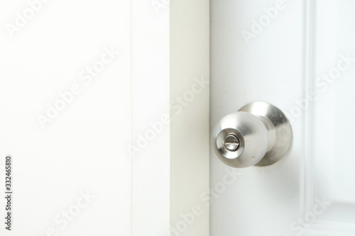 Silver doorknob on white wooden door of bathroom.