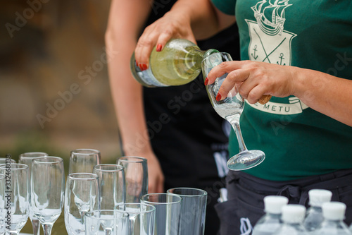 the waiter pours champagne in glasses on the street - wedding catering photo