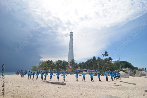 A collection of people in front of the lighthouse during the day.