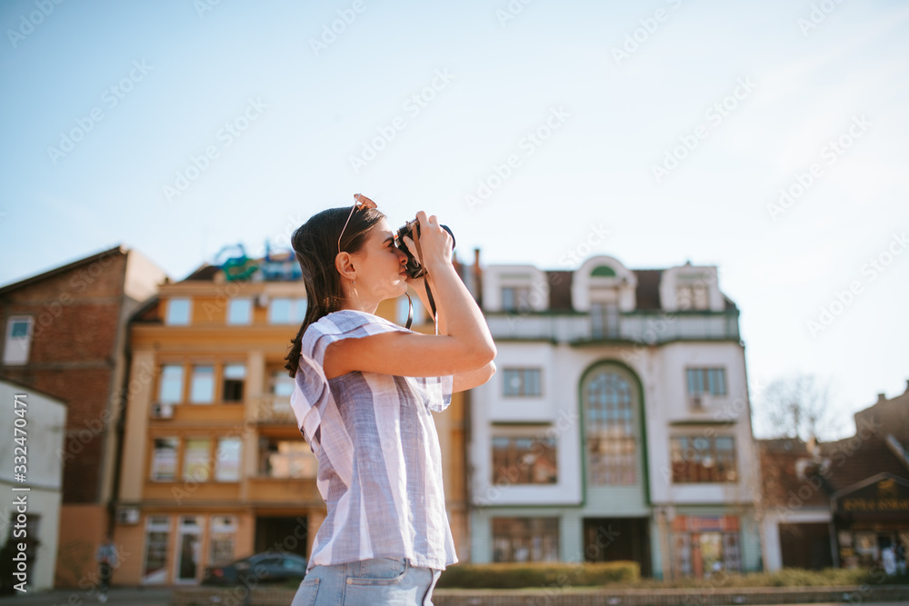  A young caucasian beautiful girl is taking a photo with a camera next to the monument