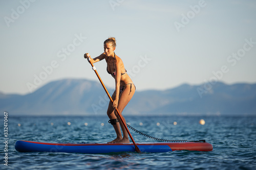 Schilderij op canvas Fit young woman paddling on sup board