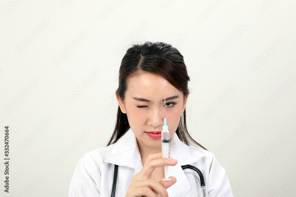 Young asian chinese doctor holding injection syringe needle look at needle with one eye on white background Young asian chinese doctor holding injection syringe needle look at needle with one eye on white background