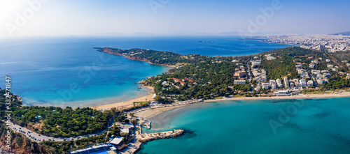 Luftaufnahme des Astir luxus Strandes und des Vouliagmeni Strandes an der südlichen Riviera von Athen, Griechenland, mit türkisem Meer und blauem Himmel