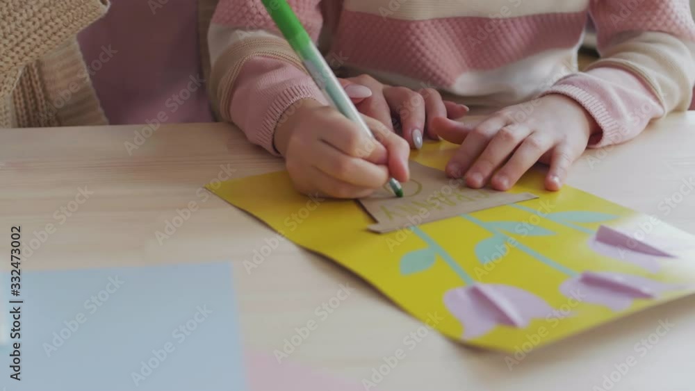 Close up of unrecognizable woman and her child making handmade cutout using green felt-tip pen Close up of unrecognizable woman and her child making handmade cutout using green felt-tip pen