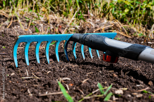 Pflanzboden wird mit einer Gartenharke bearbeitet photo