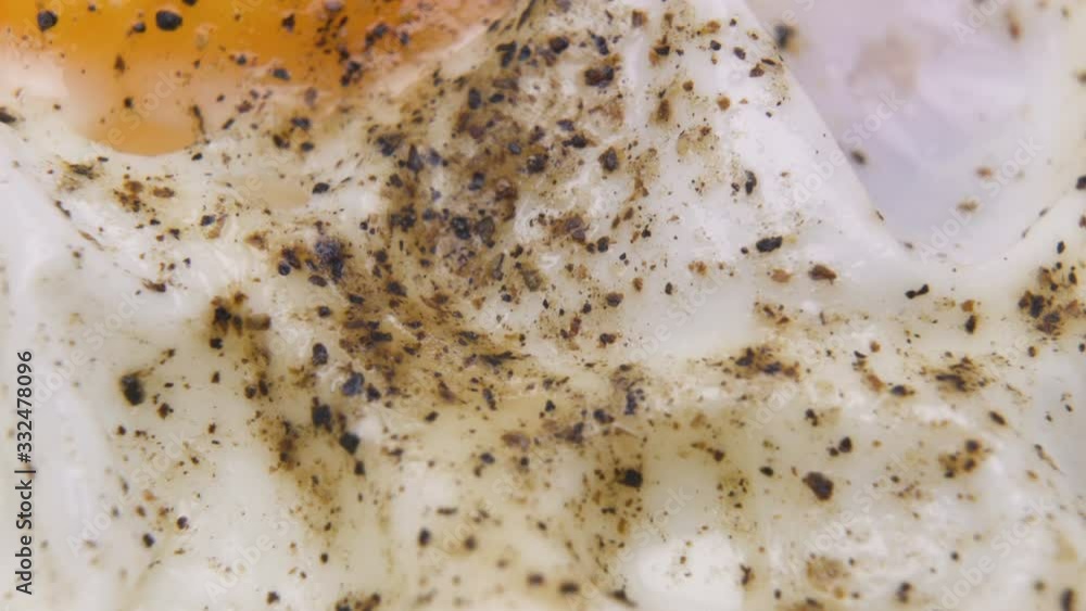 Double fried eggs with black pepper and salt on top, macro shot Double fried eggs with black pepper and salt on top, macro shot