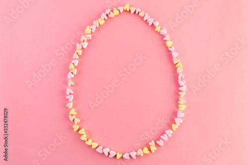 Easter egg shape made of pink and yellow marshmallows hearts. Colorful and bright holiday concept. Flat lay.