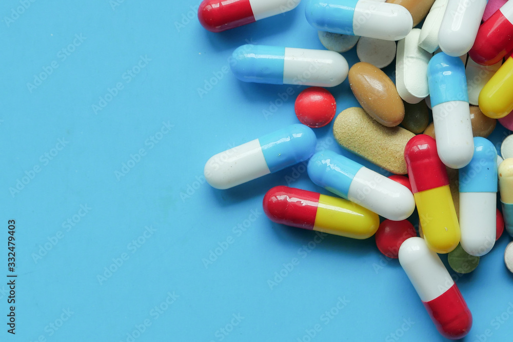  colorful pills spilling on blue background, top view