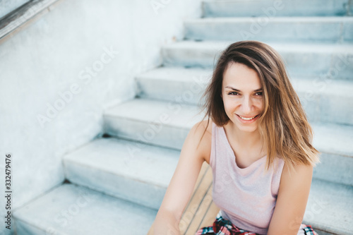 Attractive woman relaxing on the steps after longboard riding.