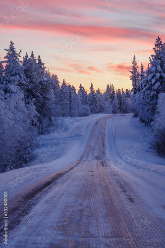 Winter scenery of a lonely icy road in Lapland at sundown, Finland