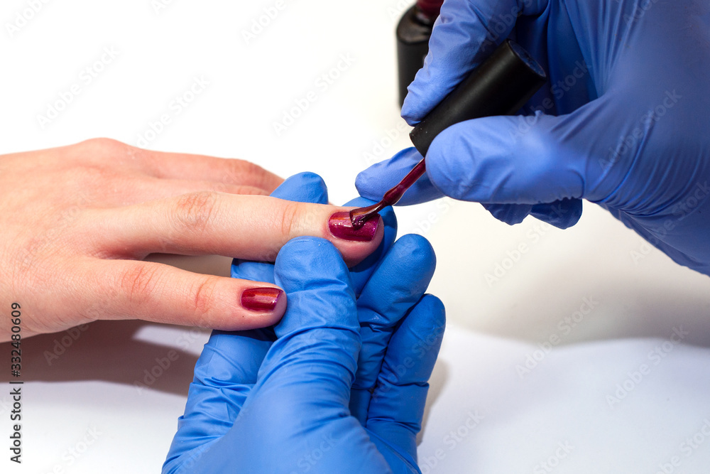manicure specialist covers the nails with red varnish manicure specialist covers the nails with red varnish