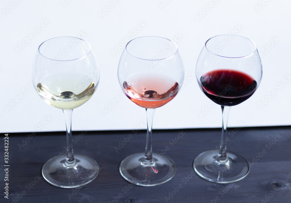 three glasses of different colors of wine on black wooden table and white wall background three glasses of different colors of wine on black wooden table and white wall background