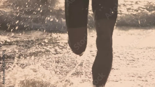 Slow-motion of a swimmer legs running out of the water at the beach photo