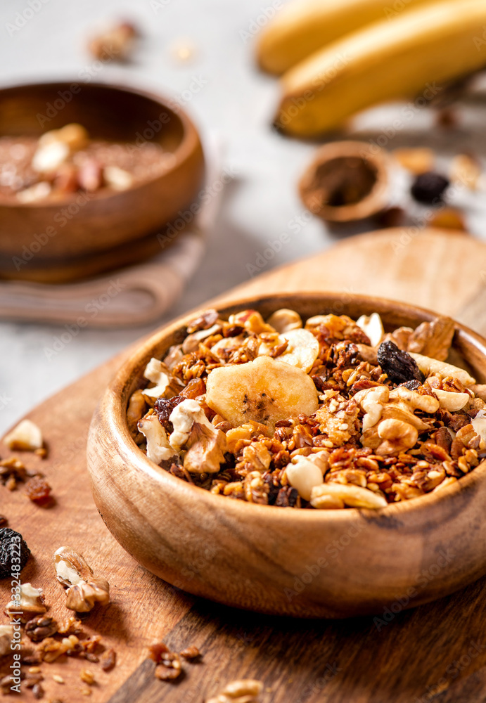Homemade toasted granola with oats, honey, walnuts, raisins, flax and sesame seeds in a wooden bowl closeup, front view, selective focus. Healthy vegetarian breakfast Homemade toasted granola with oats, honey, walnuts, raisins, flax and sesame seeds in a wooden bowl closeup, front view, selective focus. Healthy vegetarian breakfast