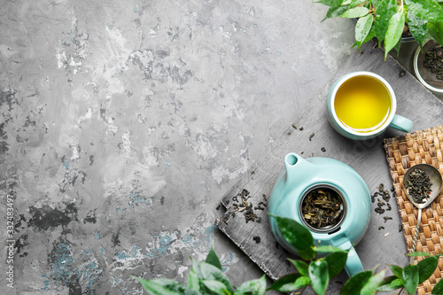 A cup of green tea in a blue cup on a gray concrete background. Cup of green tea with a teapot on a gray concrete background with copy space. Top view photo