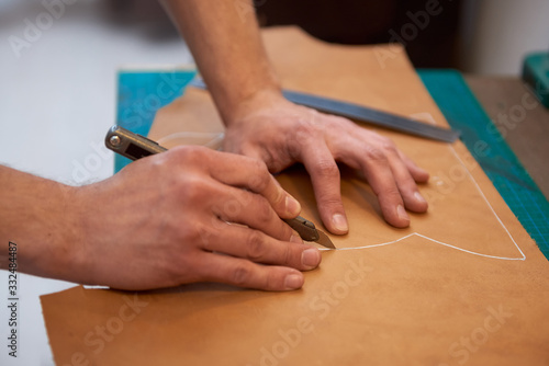 Cutting genuine leather with knife. Working process of leather craftsman. Close up of leather cutting.