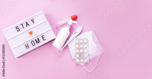 Light box with words stay at home on a pink background with drugs against the virus.