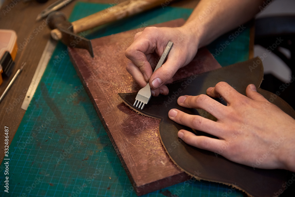 Close up of leather master hands working with natural leather and craft tools. Leather and the craft tools. Close up of leather master hands working with natural leather and craft tools. Leather and the craft tools.