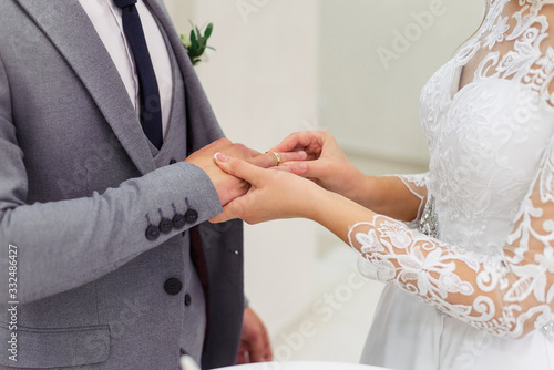 Wedding ceremony in the registry office. The bride puts a wedding ring on the finger of the groom. Close-up.