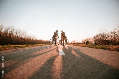  Two caucasian middle-aged cyclists stand on the road