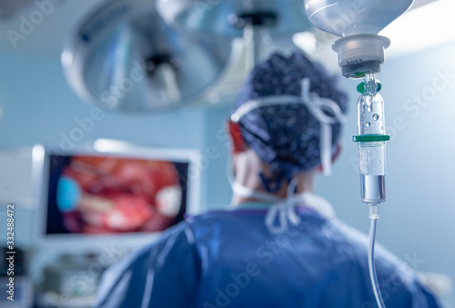 cirujano en quirofano con gotero mirando en pantalla photo