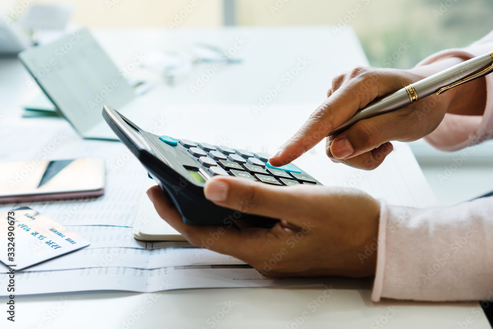 Fototapeta premium Young Asian woman Calculating monthy expense at her desk. Home saving concept. Financial and Installment payment concept. Close up.