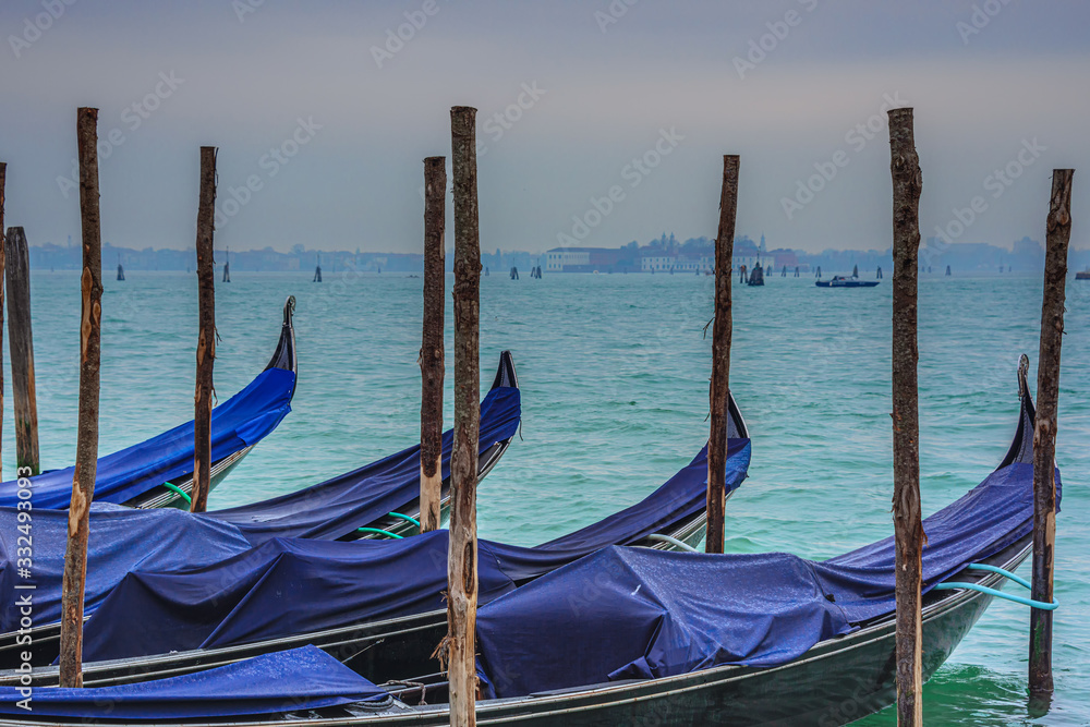 Pier with moored gondolas on Saint Mark square with view over lagoon at wintertime Pier with moored gondolas on Saint Mark square with view over lagoon at wintertime