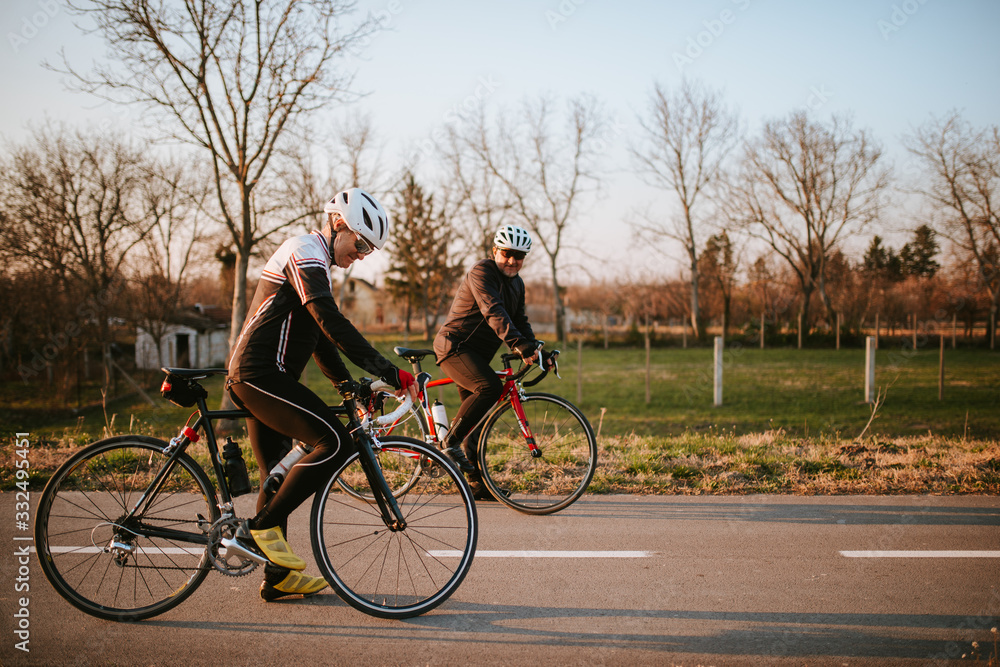 Fototapeta premium Two middle-aged men ride a bicycle on a road