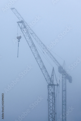 view of construction cranes in the fog