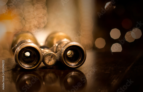 Still life with an old wood earth globe and a retro binoculars with a bokeh background.