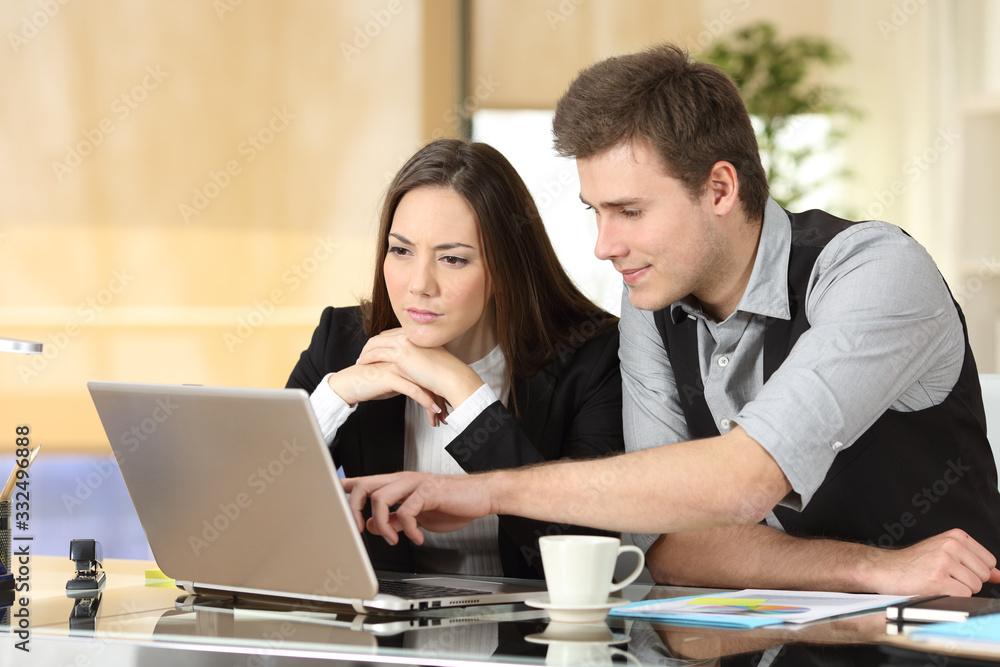 Coworkers working together checking laptop content Coworkers working together checking laptop content