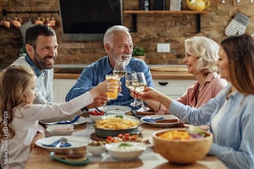 Happy extended family toasting during lunch at dining table.