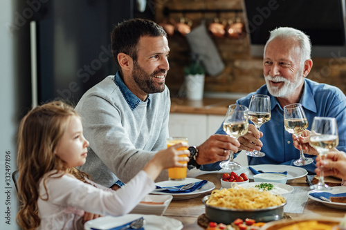 Happy man toasting with his family during lunch at dining table.