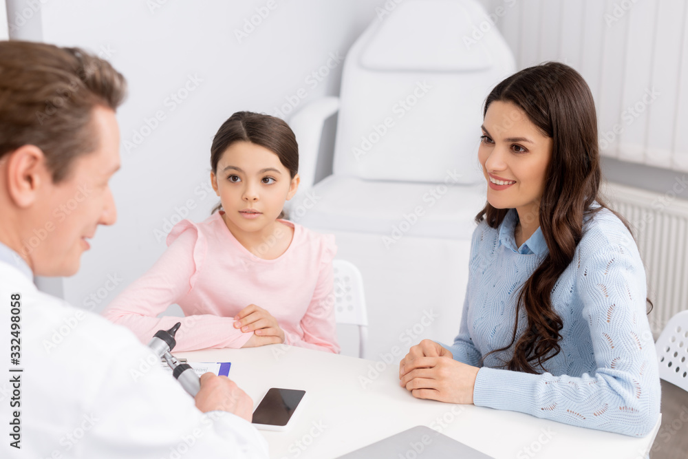 smiling woman with cute daughter on consultation with ent physician smiling woman with cute daughter on consultation with ent physician