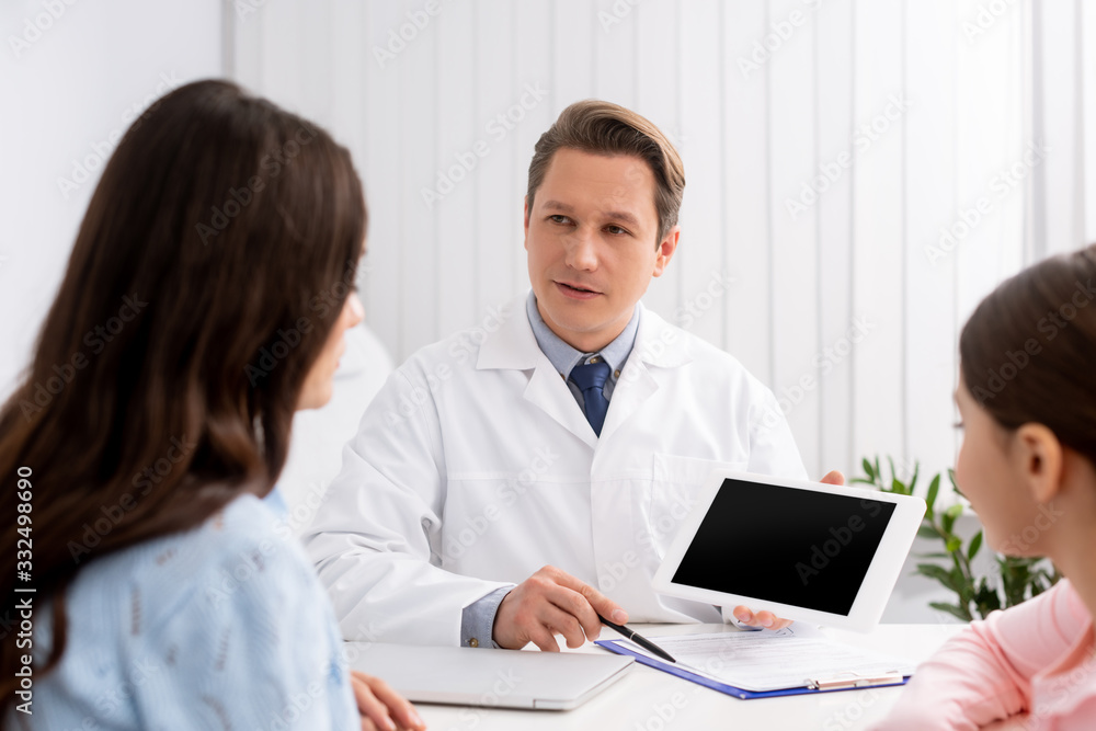 back view of mother and daughter near otolaryngologist holding digital tablet with blank screen back view of mother and daughter near otolaryngologist holding digital tablet with blank screen