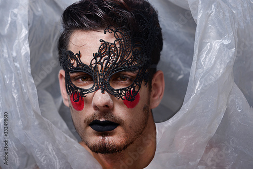 La craneo de el joker interpretado por el joven actor gay con mascara y lavios negros, de vestuario nailon reciclado . expresión melancólica
