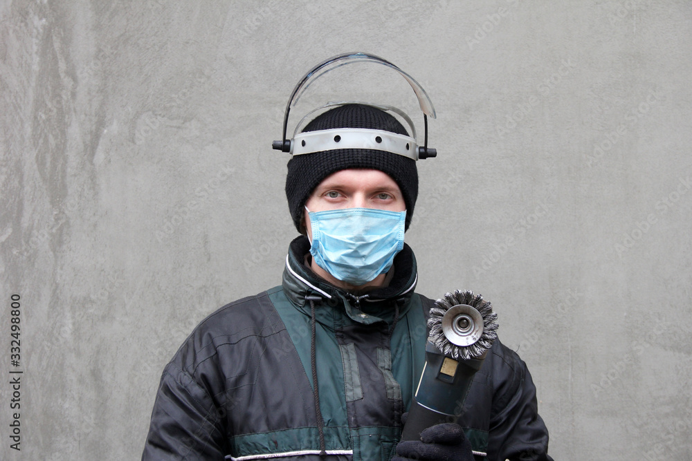 Masked man with grinder in hands. Worker in dirty clothes Masked man with grinder in hands. Worker in dirty clothes