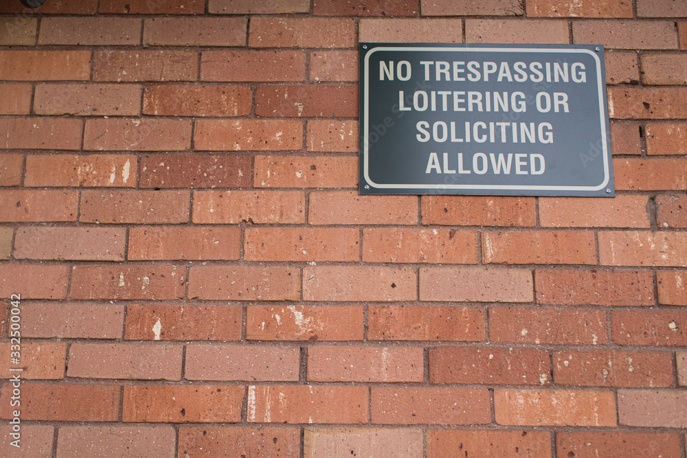 No trespassing or loitering sign on brick building No trespassing or loitering sign on brick building