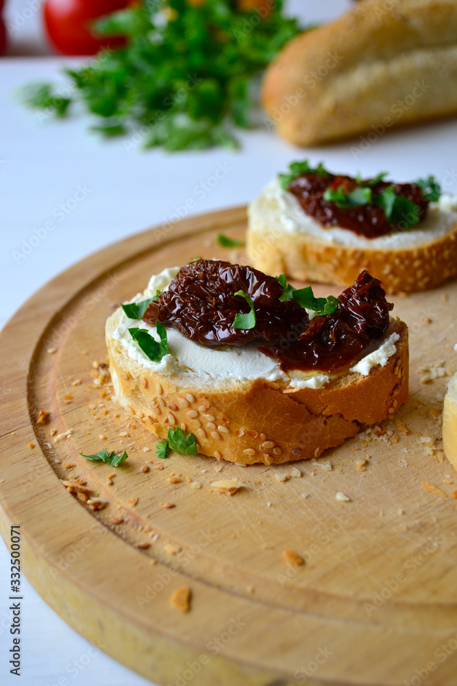 French baguette with cream cheese and dried tomatoes on a white background. French baguette with cream cheese and dried tomatoes on a white background.
