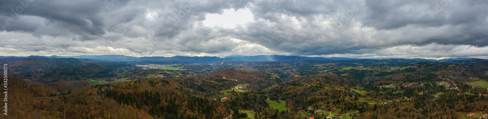 Panorama of notranjska region of slovenia in autumn colors, with dense clouds carrying storm approaching. Beautiful autumn weather viewed from Ulovka, visible mount Sneznik and Javornik.