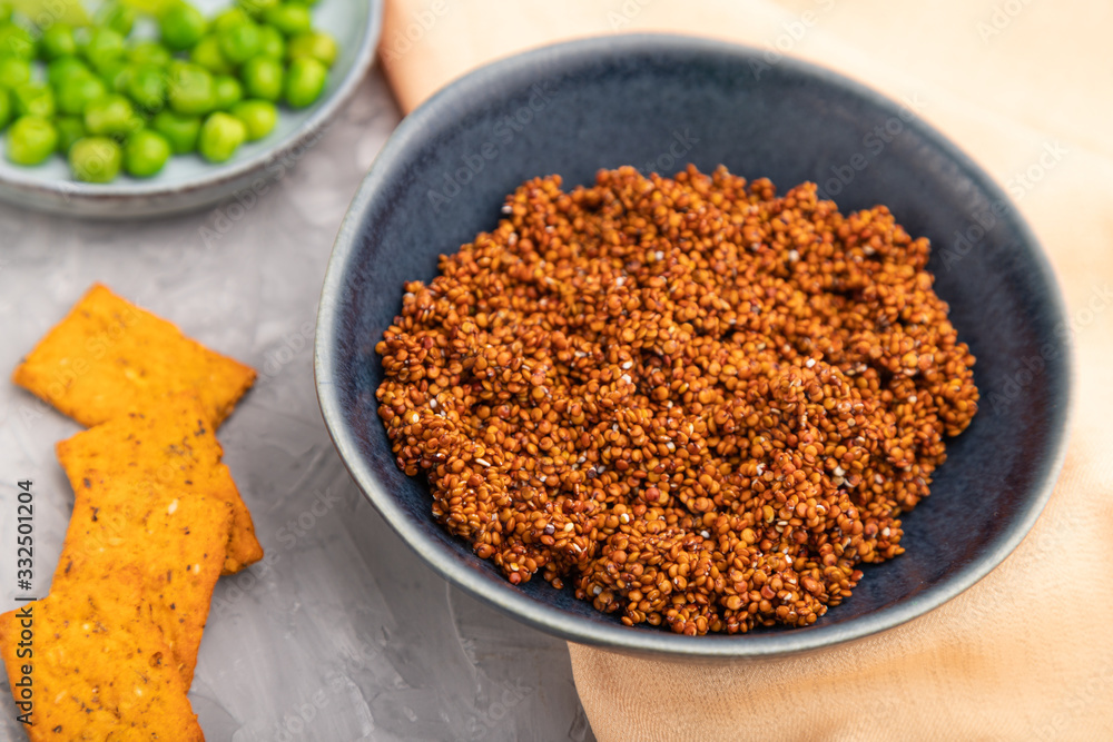 Raw quinoa in ceramic bowl on a gray concrete background and orange textile. Side view. Raw quinoa in ceramic bowl on a gray concrete background and orange textile. Side view.