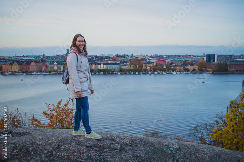 Young woman is posing on the Skinnarviksberget lookout viewpoint, way above the Stockholm. Cityscape of stockholm is seen in the background. photo