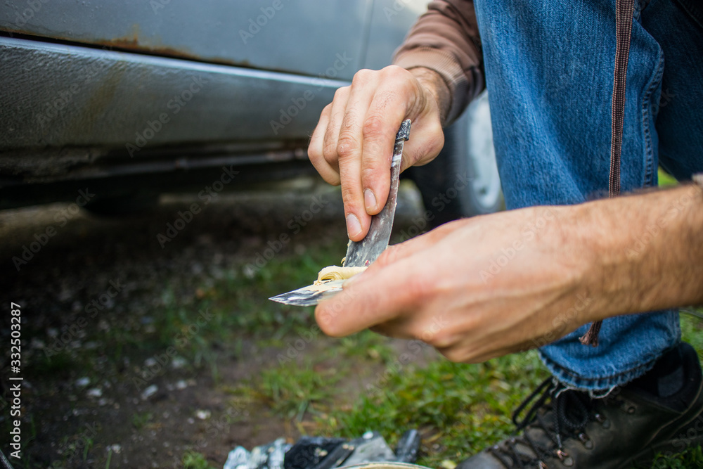 Detail of an amateur mechanic applying polyester putty to repair the