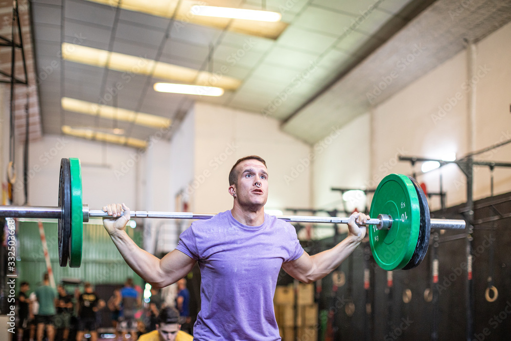 Muscular guy lifting barbell in modern gym Muscular guy lifting barbell in modern gym