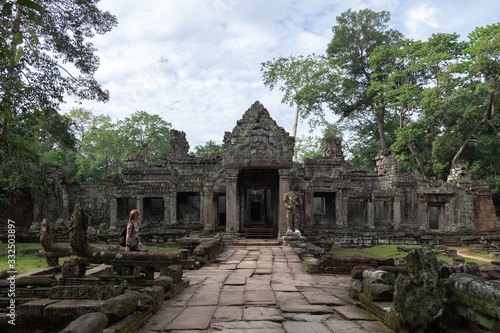 Side view of woman enjoying vacation while looking at ruins of religious temple of Angkor Wat in Cambodia photo