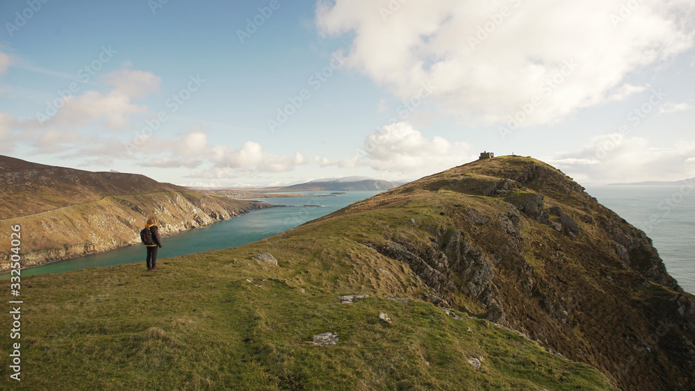 Back view of unrecognizable woman enjoying wonderful nature landscape and sea while standing on cliff in Ireland looking away Back view of unrecognizable woman enjoying wonderful nature landscape and sea while standing on cliff in Ireland looking away