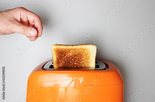 hand toast and orange toaster on a light background фототапет